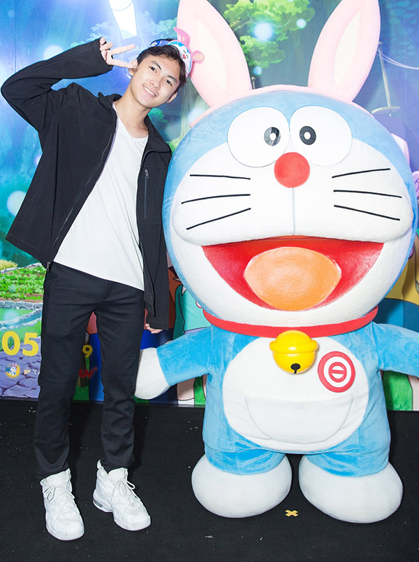 Sao nhí Thịnh Vinh tạo dáng xì tin bên mèo máy Doraemon bằng bông.